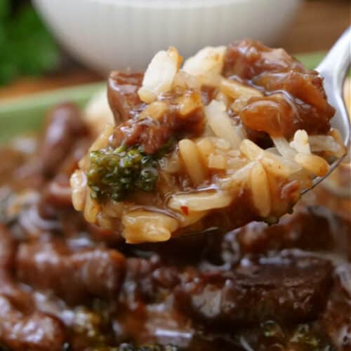 A close up of a spoonful of beef, broccoli, and rice.