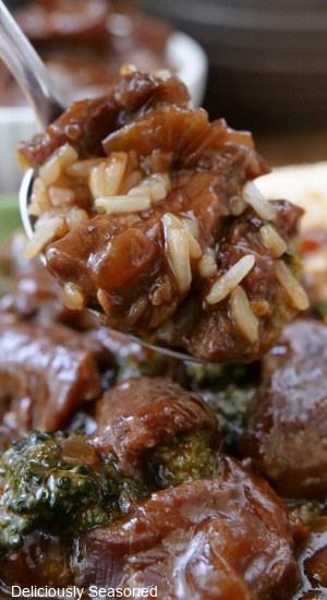 A close up of spoonful of rice, broccoli, and beef.