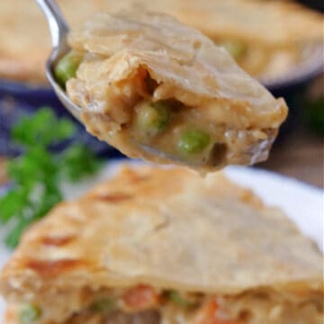 A close up of a bite of beef pot pie on a spoon.