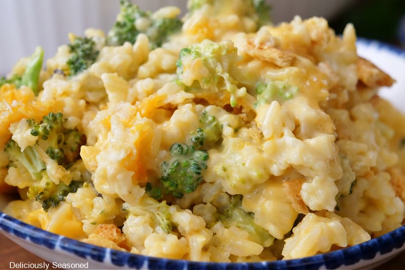 A horizontal photo of a serving bowl filled with broccoli, rice, and cheese.
