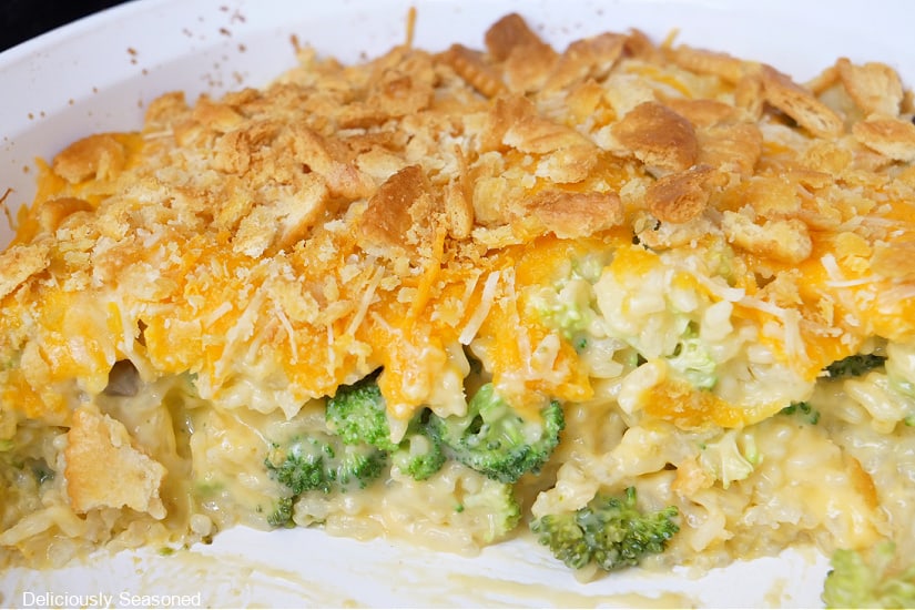 A white casserole dish with broccoli cheese rice casserole in it.