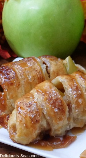Two puff pastries filled with apple slices on a white plate.