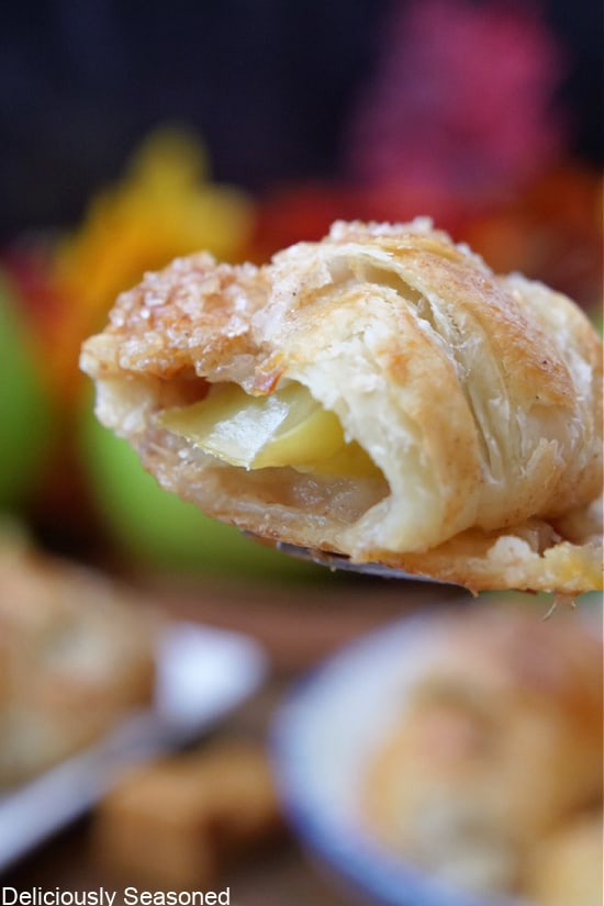 A baked apple sliced wrapped in puff pastry with a bite taken out of it.