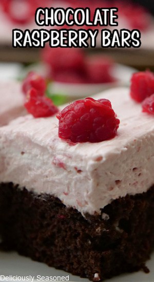 A close up of a chocolate bar with raspberry whipped cream and coarsely chopped raspberries on top.