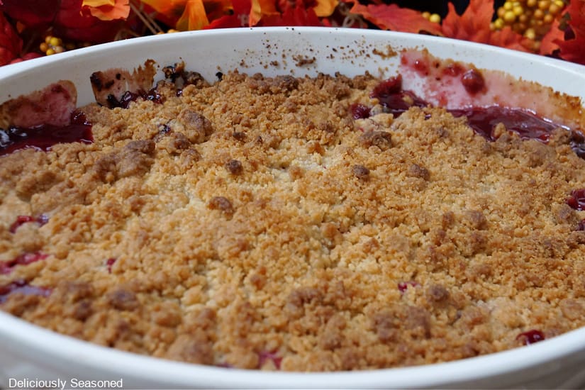 A horizontal photo of an oval baking dish filled with baked cranberry crisp.
