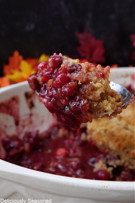 A large spoonful of cranberry crisp being scooped out of the baking dish.
