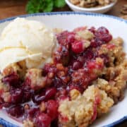 A bowl of cranberry crisp with a scoop of vanilla ice cream.