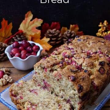 A loaf of cranberry walnut bread on a white rectangle plate with blue trim.