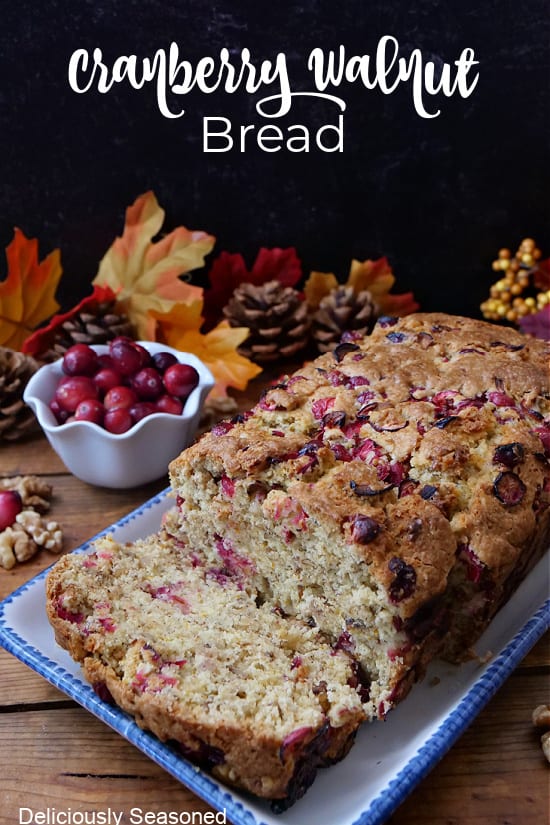 A loaf of cranberry walnut bread on a white rectangle plate with blue trim.