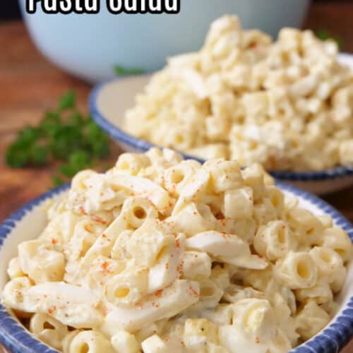 Two white bowls with blue trim with a serving of deviled egg pasta salad in each bowl.