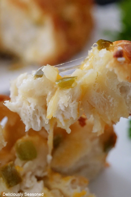 A super close up photo of a piece of cheesy monkey bread showing the gooey cheese and diced jalapenos.