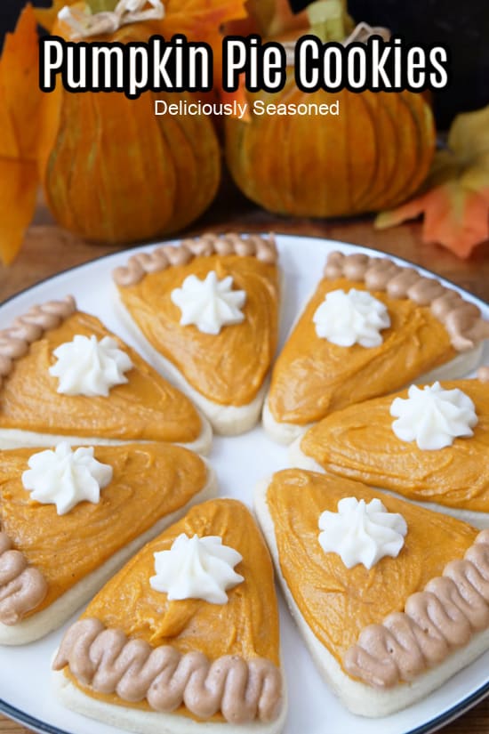 A white round plate with pumpkin pie shaped sugar cookies decorated like a slice of pumpkin pie.