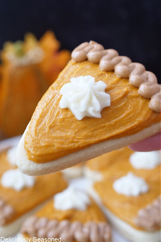 A close up of a sugar cookie decorated like a slice of pumpkin pie.