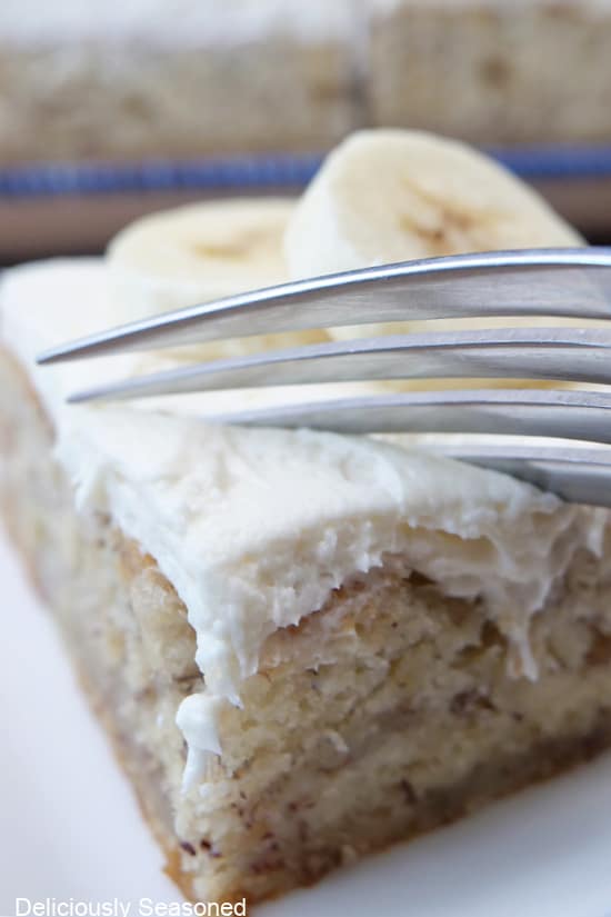 A close up of a banana bar with a fork getting ready to cut of a bite out of it.