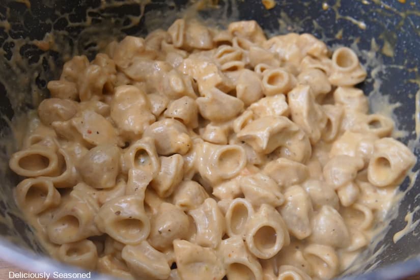 A pan filled with creamy pasta and bite-size pieces of chicken.