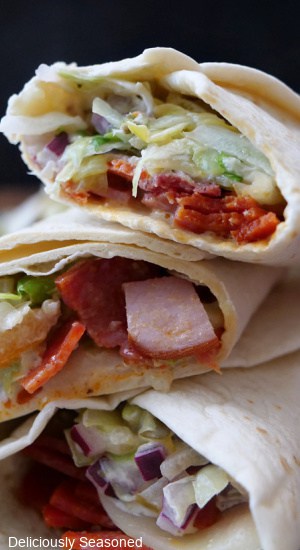 A close up of a stack of three chopped Italian wraps on top of each other.