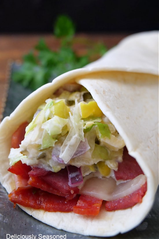 A flour tortilla filled with chopped meat, cheese, and a lettuce mixture.