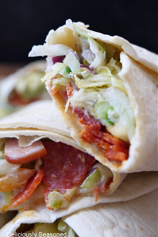A close up of a few chopped Italian wraps on top of each other with a bite taken out of one of them.