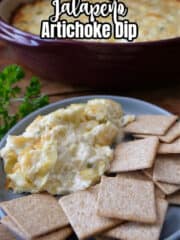 A light blue plate with wheat thins and a scoop of homemade jalapeno artichoke dip on it.