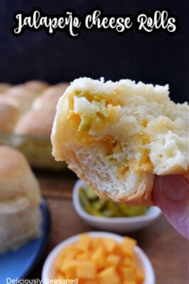 A jalapeno cheese dinner roll with a bite taken out held up close to the camera lens.