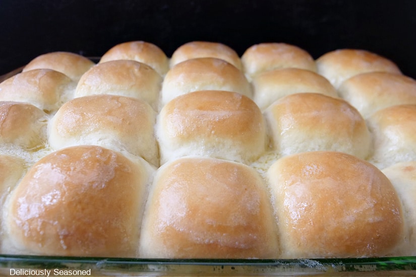 A baking dish pulled right out of the oven with twenty homemade dinner rolls in it.