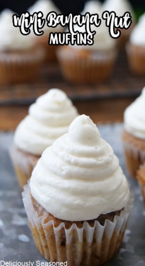 A close up of two mini banana muffins with cream cheese frosting on them.