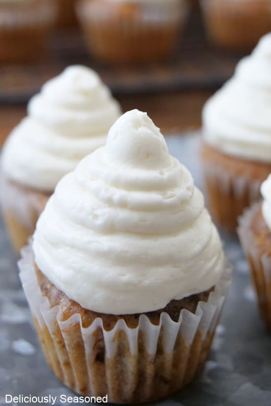 A super close up of a photo of a bite-size banana nut muffin with cream cheese frosting on top.