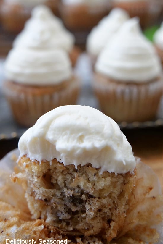 A bite-size muffin with cream cheese frosting that has a bite taken out of it.
