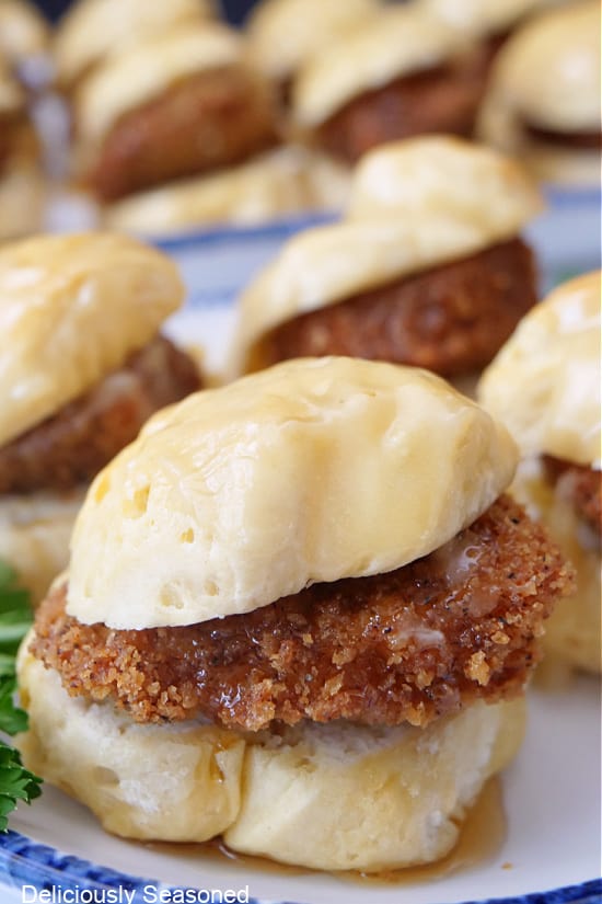 A close up of a mini biscuit with a piece of fried chicken and honey butter on it.