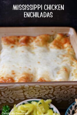 A tan baking dish filled with chicken enchiladas after being removed from the oven.