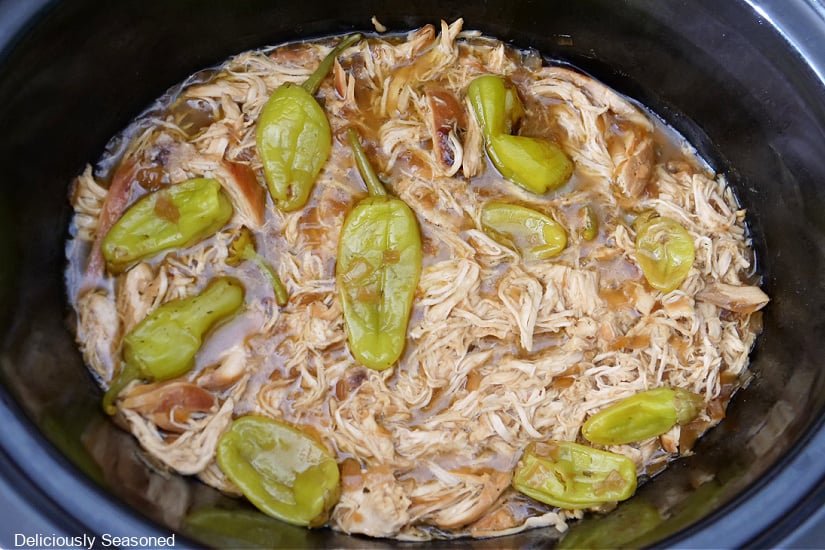 A horizontal photo of a crock pot filled with shredded Mississippi Chicken.