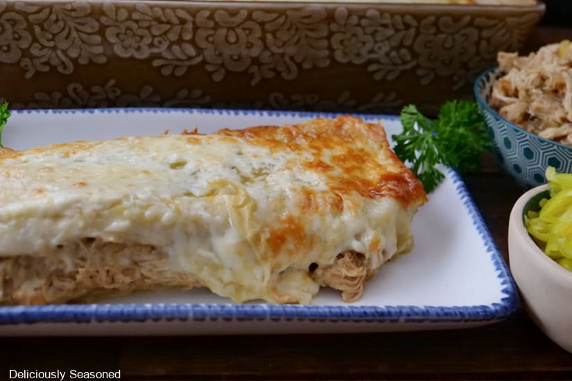 A white rectangle plate with blue trim with a chicken enchilada on it.