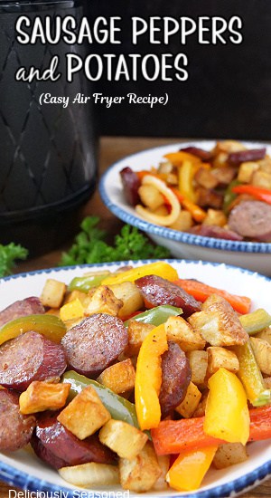 Two white bowls with blue trim filled with air fried sausage, peppers, and potatoes.