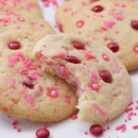 A close up of a few sugar cookies with red and pink candy on them.
