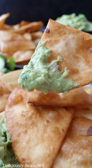 A close up photo of a homemade deep fried flour tortilla chip with guacamole on it.