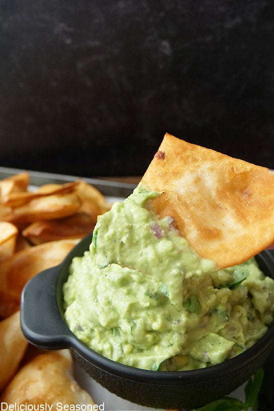 A close up of a homemade flour tortilla chip that was dipped in homemade guacamole.