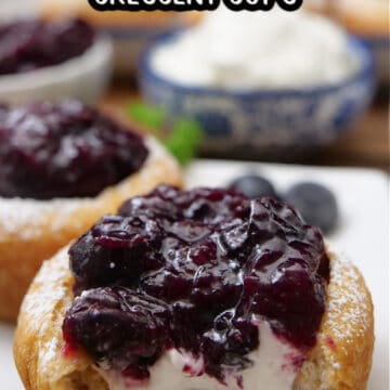 A close up of a crescent dough cup filled with sweet cream cheese and topped with blueberries.