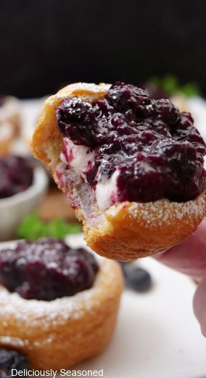 A crescent cup filled with a cream cheese mixture and blueberry topping with a bite taken out of it.