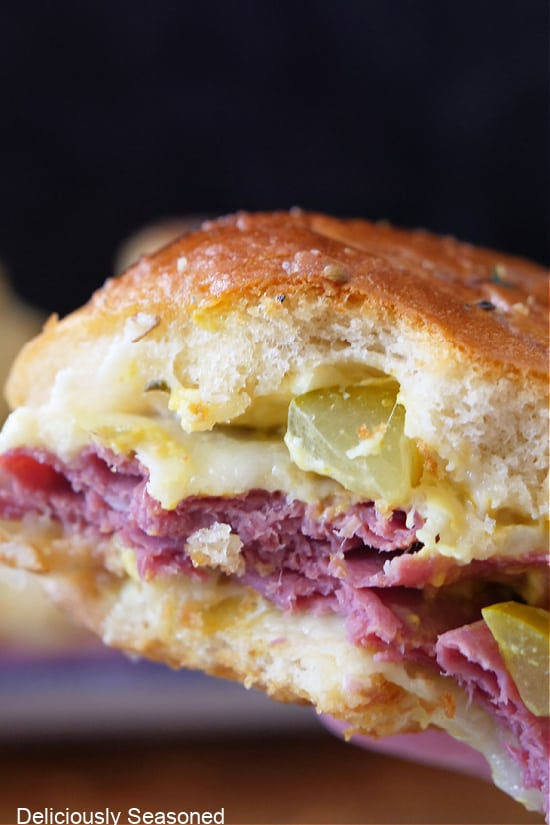 A close up of a pastrami slider with a bite taken out of it.