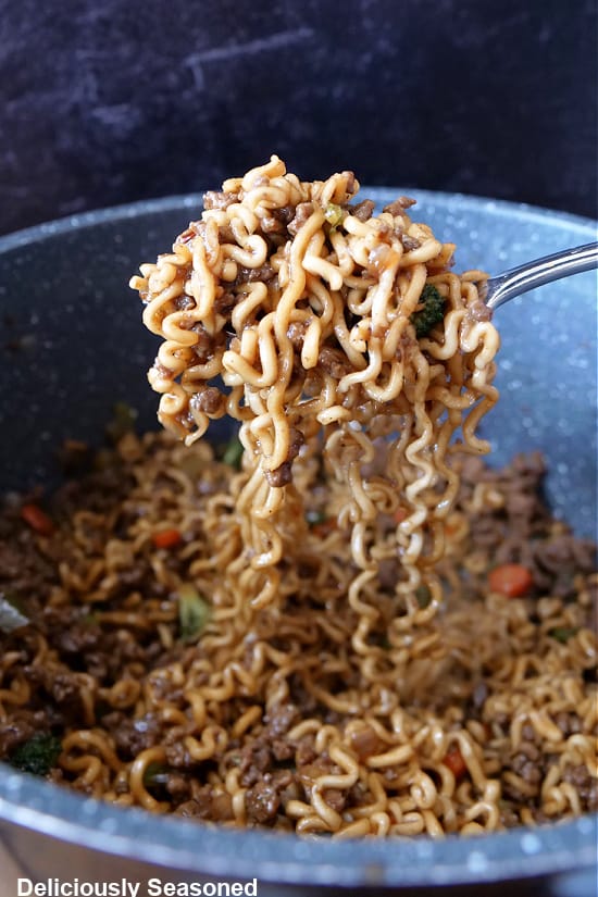A large spoonful of ramen noodles being scooped out of the pan.