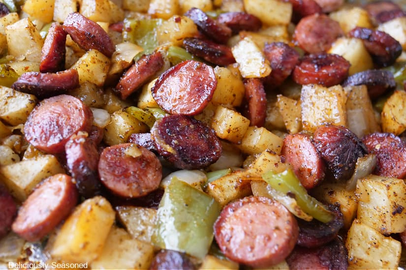 A close up of sliced sausage, diced potatoes, bell pepper and onions.