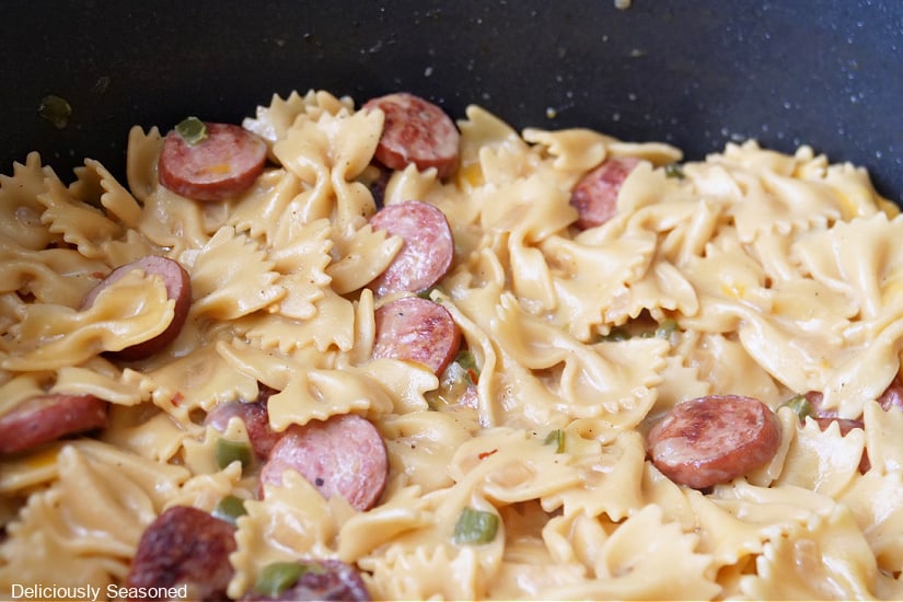 A pan filled with sausage and pasta in a creamy sauce.