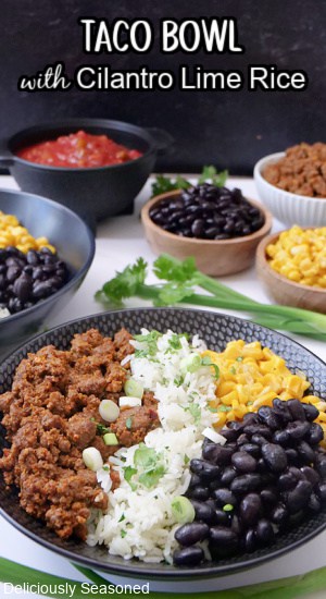 Two black bowls filled with cilantro lime rice, black beans, corn, cheese, and taco meat.