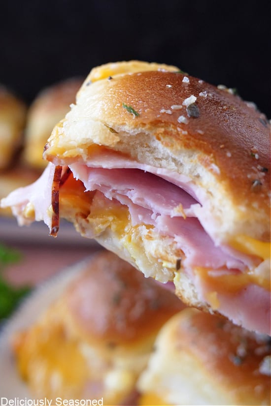 A close up of a bite taken out of a ham and cheese slider.
