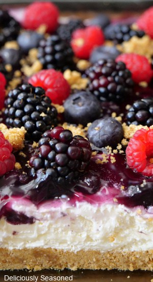 A close up photo of a graham cracker crust with a sweet cream cheese layer and topped with fresh berries.