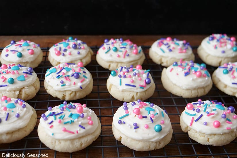 A horizontal photo of a cooking rack with 14 frosted sugar cookies on it.