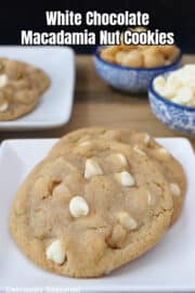 A white small plate with two white chocolate macadamia nut cookies on it.