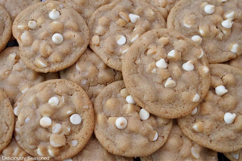 Lots of white chocolate chip cookies pile all over each other.