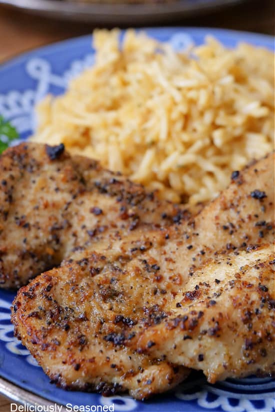 A close up of lemon pepper chicken strips on a blue plate.