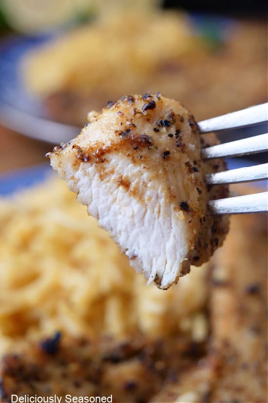 A close up of a bite of chicken on a fork.